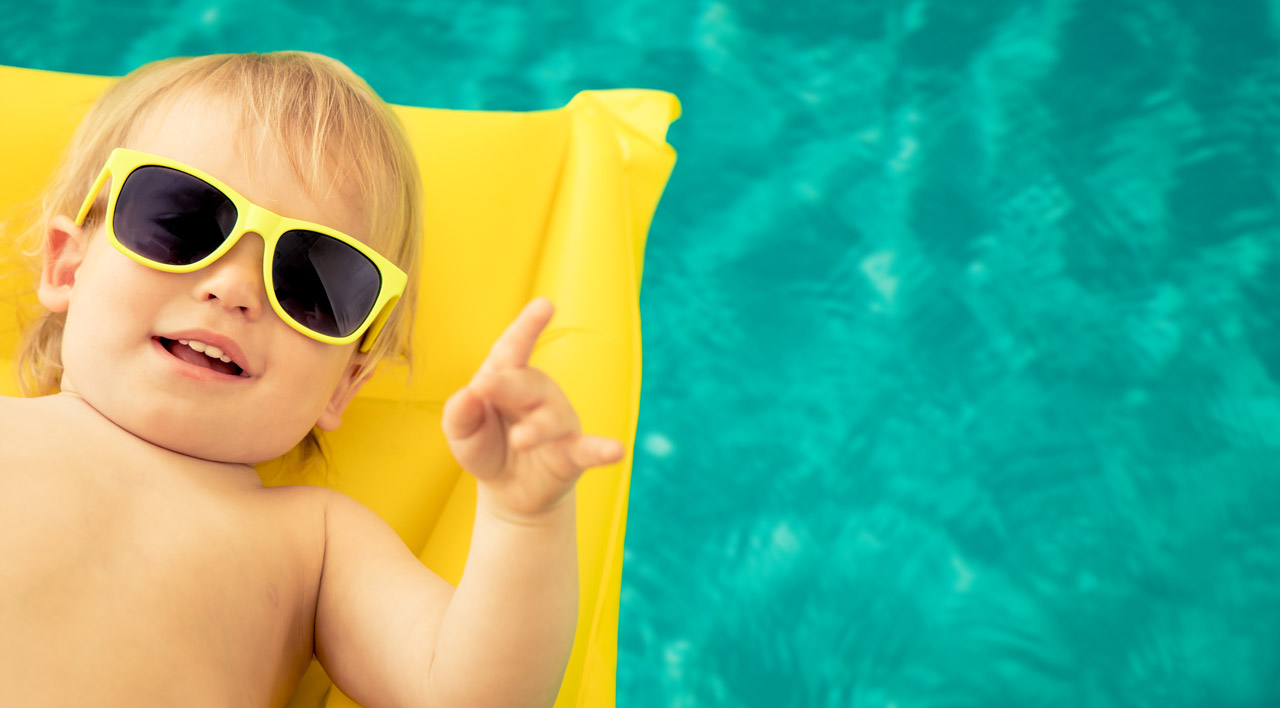 Kid floating in pool with hands signaling excitement
