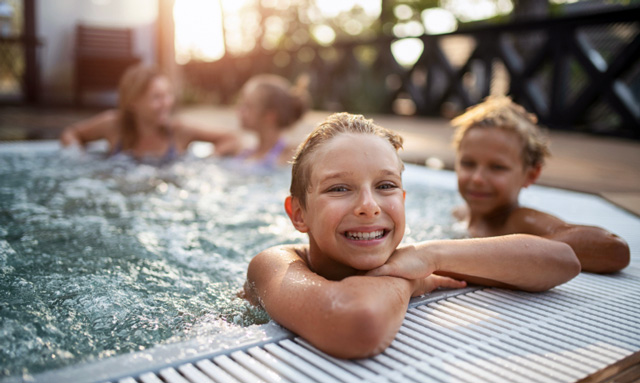 Two boys and their mothers relax in a hottub.